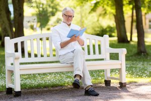 happy senior man reading book at summer park