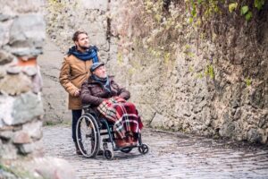 Senior father in wheelchair and son on a walk in old town.